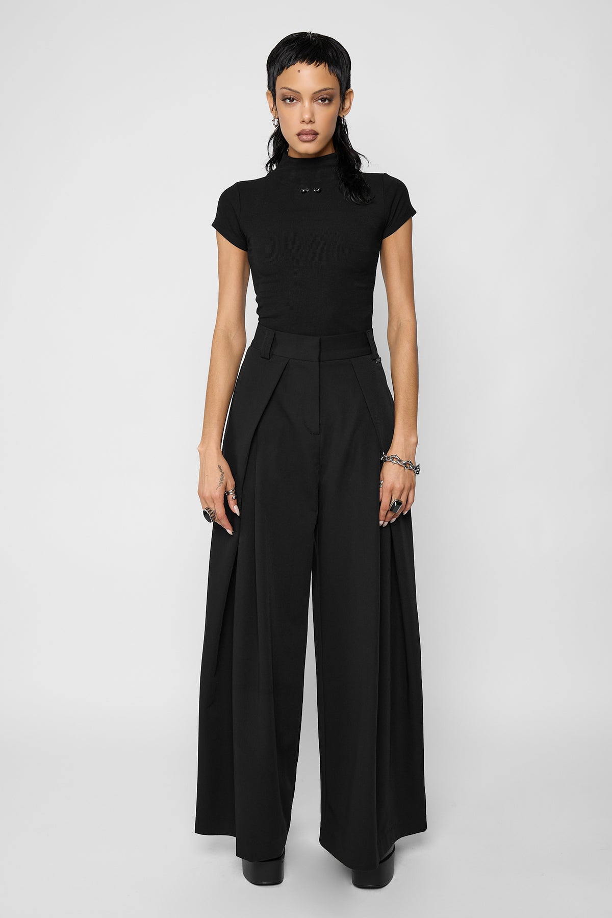 Full-length front view of a model wearing the black ribbed Madison top with black high-waisted wide-leg pleated trousers and black platform shoes.